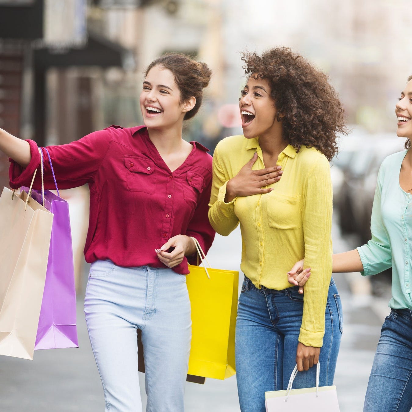 Teens with shopping bags walking on a street.