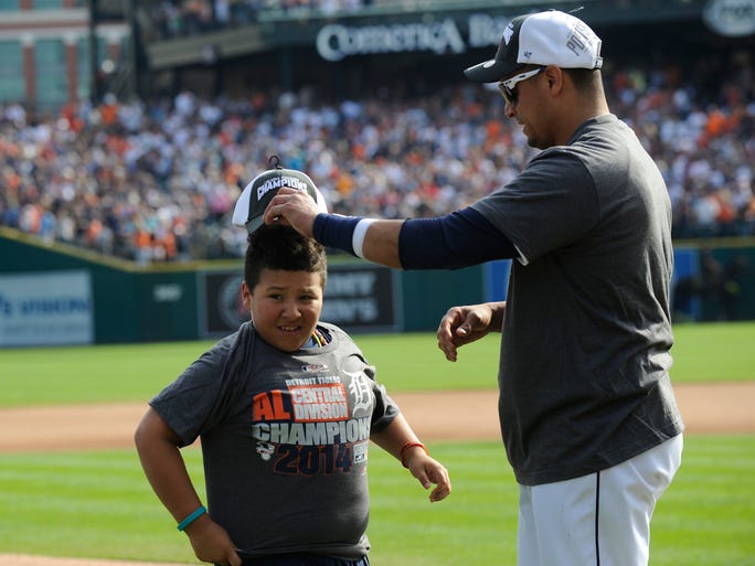 Tigers' Victor Martinez (1) puts an AL Central championship hat on his son Victor during the postgame celebration.