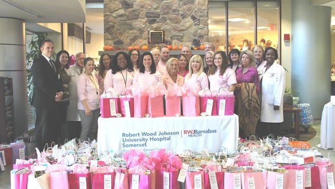 Somerset County employees and volunteers and Robert Wood Johnson University Hospital Somerset executives, physicians and staff with Freeholder Patricia L. Walsh (first row, fifth from the right) and Tara Kenyon (to Walsh's right) at the fifth annual Pink Out presentation of donated items for patients and caregivers at the medical center. The event was spearheaded by Somerset County Planning Board Principal Planner Tara Kenyon of Manville, a cancer survivor who was diagnosed and successfully treated four years ago. Shown are just a few of the hundreds of comfort bags that were assembled by employees and volunteers for distribution.