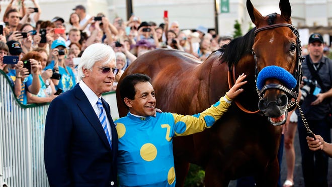Trainer Bob Baffert and Jockey Victor Espinoza pose for pictures with American Pharoah in the paddock at Churchill Downs. June 13, 2015. 