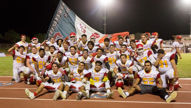 The Palm Desert High School football team celebrates with the Victory Flag after beating rival La Quinta 24-17 in triple overtime on Friday night.