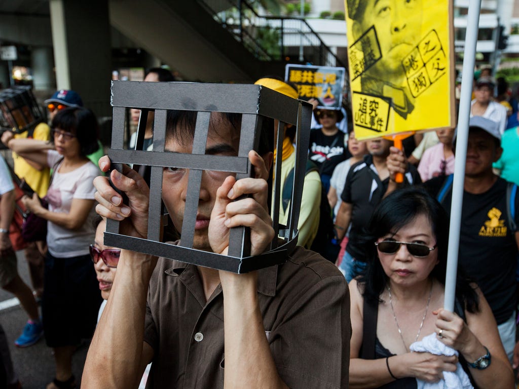 Hong Kong people and lawmakers march through the streets wearing prison uniforms and 'cages' on their heads as a statement in support of imprisoned student political activists Joshua Wong, Nathan Law and Alex Chow on Aug. 20, 2017. On Aug. 17, the Co