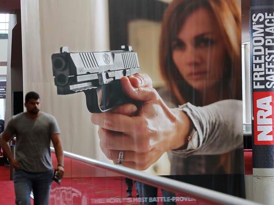 A attendee passes by a large banner advertising a handgun