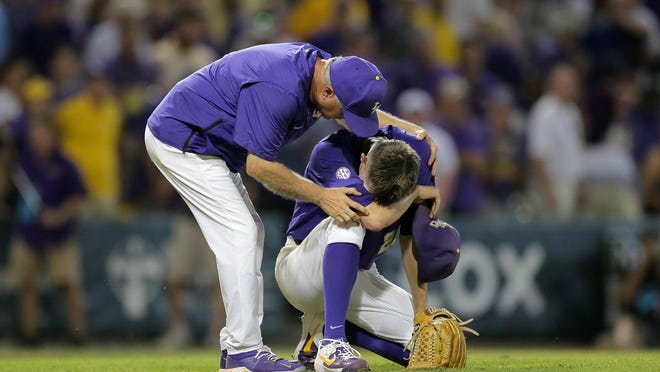 LSU pitcher Devin Fonenot is comforted by head coach Paul Mainieri, after losing Game 2 of the NCAA college baseball super regional tournament to Florida State, 5-4, in the 12th inning in Baton Rouge, La., Sunday, June 9, 2019. (David Grunfeld/The Times-Picayune via AP)