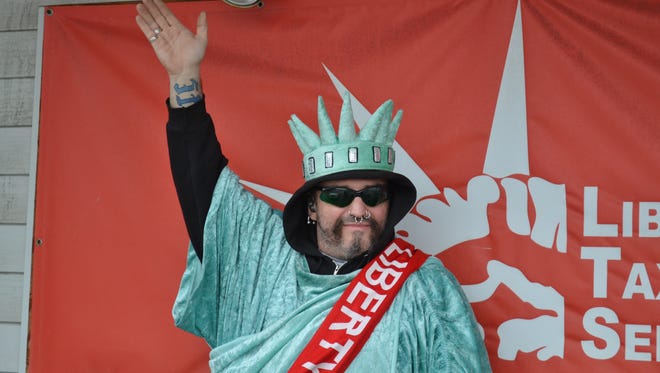 A waving Lady Liberty is an annual sign that tax season has arrived. Here, Jerry Chaffee tries to attract customers for Liberty Tax Service in Fremont. A change in the federal tax law will bring changes to tax returns filed next year.