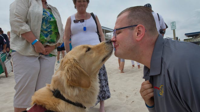 Sgt. Adam Campbell gets a kiss from his service dog Kenan as they attend the Benefit Beach Party for Paw4Vets at Chef Mike's Atlantic Bar & Grill in Seaside Park. They hope to raise $100,000 for the organization that matches returning servicemen with service dogs to help them in their daily lives. NJ on May 17, 2015. Peter Ackerman/Staff Photographer