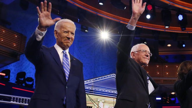Democratic presidential candidates former Vice President Joe Biden, left, and Sen. Bernie Sanders, I-Vt., wave Thursday night before the start of a Democratic debate hosted by NBC News at the Adrienne Arsht Center for the Performing Arts in Miami.