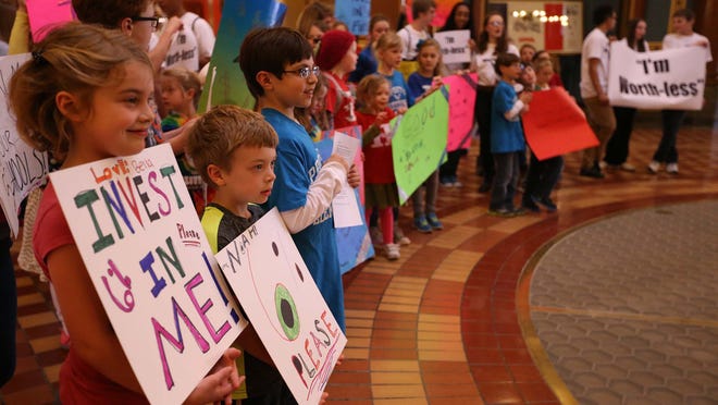 A group of children and parents carry signs through the State Capitol on Wednesday during a rally for state education funding. Divisions over kindergarten through 12th grade funding appear to have stalled the progress of the 2015 legislative session.