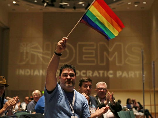 Spectators wave LGBTQ pride flags as Pete Buttigieg,