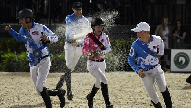 Members of the victorious men's team celebrate with champagne, while also showering a member of the women's team, after Saturday night's Battle of the Sexes at the Palm Beach International Equestrian Center in Wellington.