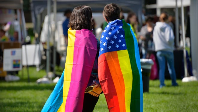 Couple Nikki Sloan, left, and Kimmy Luke of St. Cloud wear flags in support of the St. Cloud Pride celebration during the Pride in the Park event Sept. 19, 2015, at Lake George.