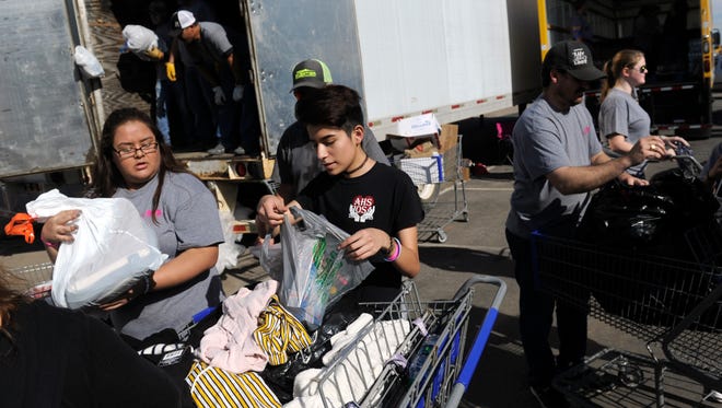 Volunteers Mya Ramos (left) and Gene Kewenvoyouma, both sophomores at Abilene High School, unpack bags of donated items Friday at Mission Thanksgiving. The annual benefit for Love & Care Ministries was held at Arrow Ford.