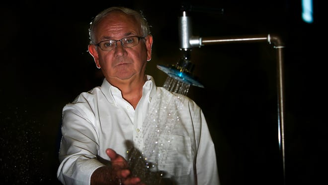 Bob Knoll, CEO of the New Castle plumping supply company Speakman, puts his hand under a low-flow Reaction shower head.