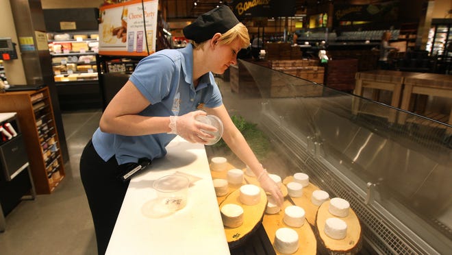 Stacy Thay, sets out French triple cream cheese at the East Avenue Wegmans store.