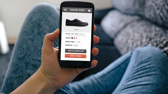 A man holding a smartphone with a picture of a shoe on it.