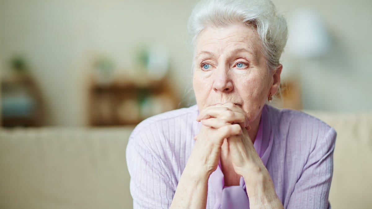 Senior woman looking worried with her hands clasped in front of her face