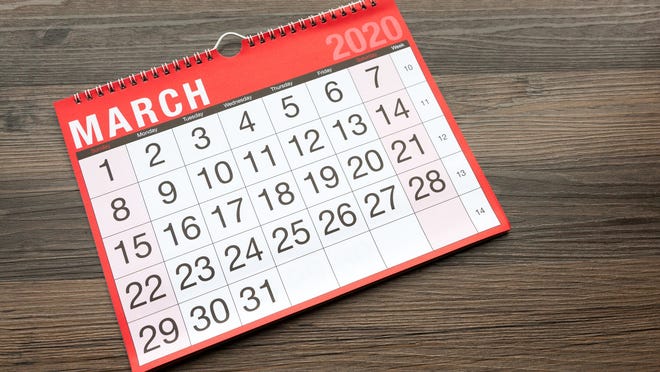 A calendar open to March 2020 on a wooden table.