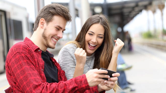 Couple cheering and excited as they play a game on a cellphone