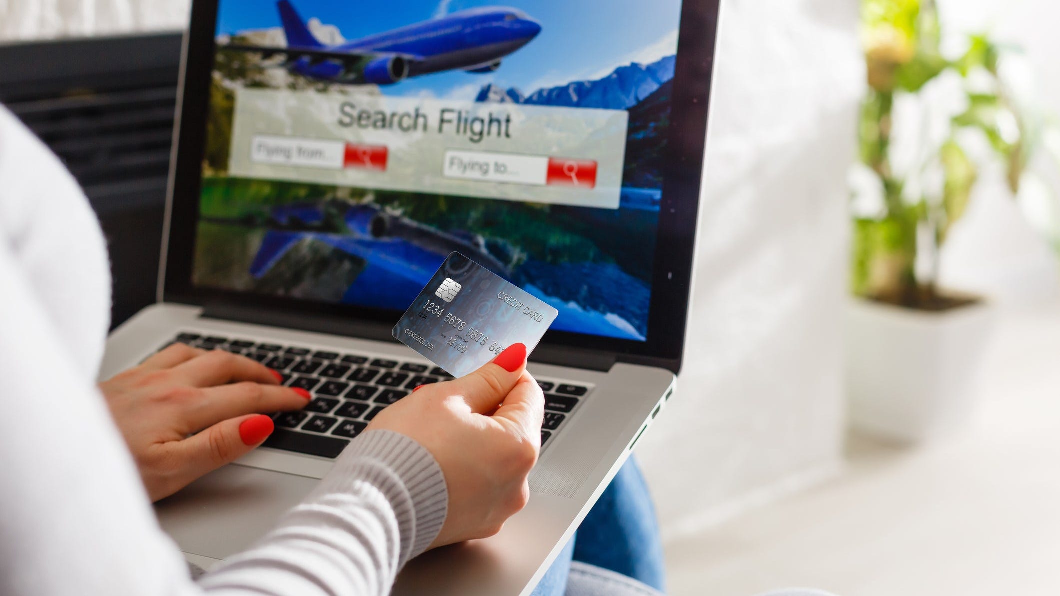 Lady holding credit card and searching for flight on laptop