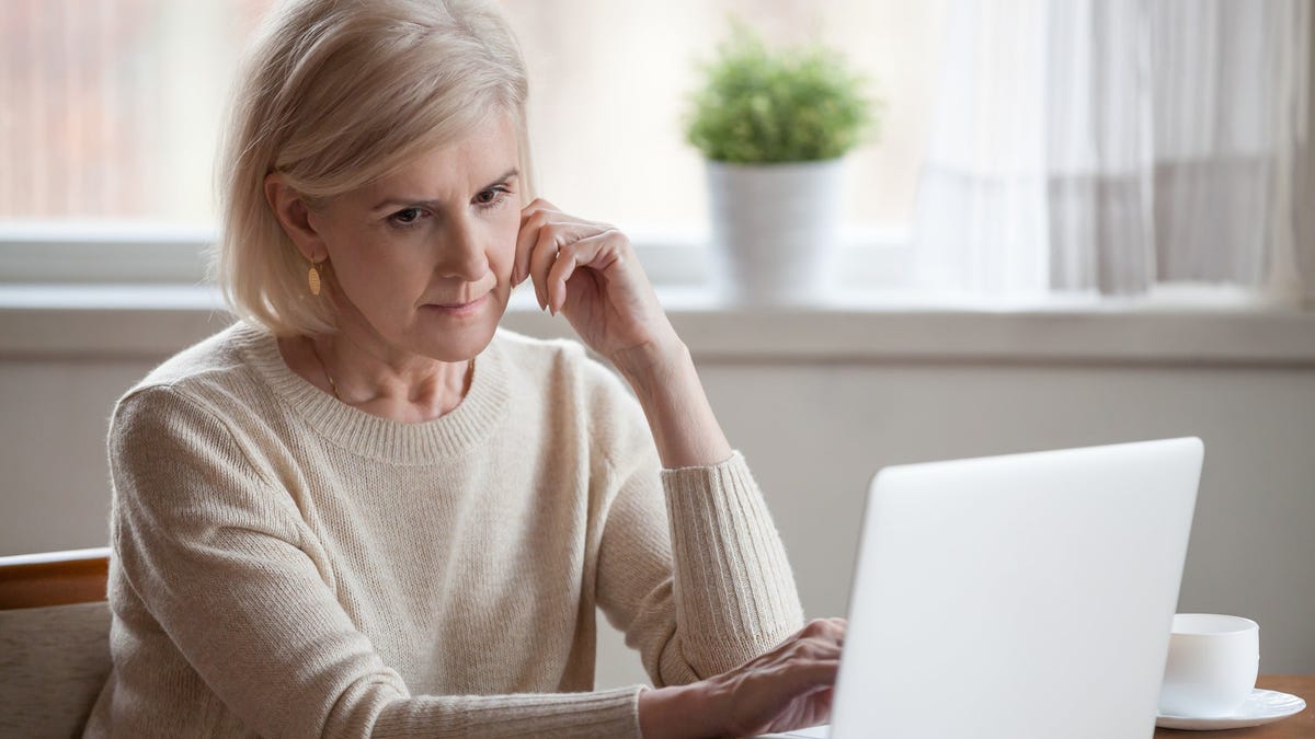 Older woman with serious expression at laptop