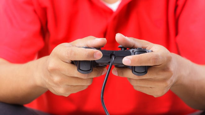 Person holding game controller in two hands, with left thumb raised.