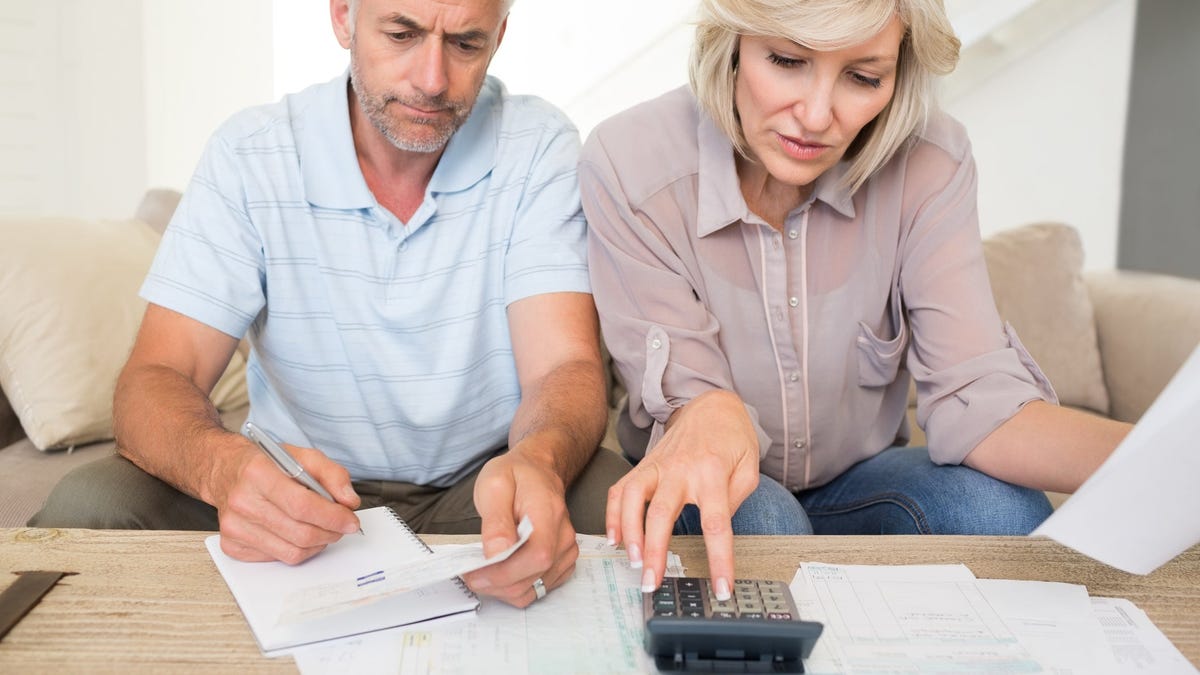 Older couple looking at financial papers with calculator.