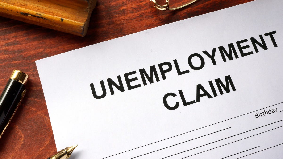 Unemployment claim document on table with open pen resting on it