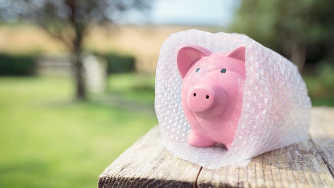 A piggy bank is shielded by bubble wrap, representing the concept of savings protection.