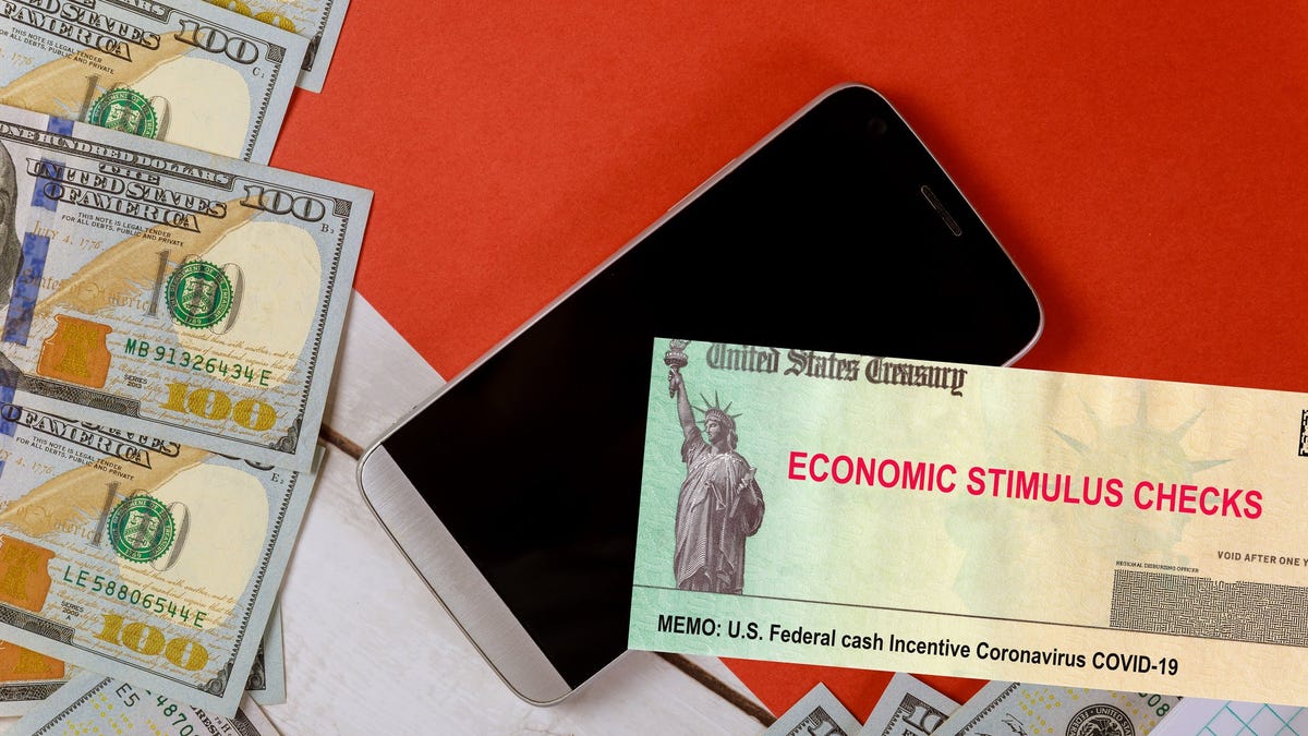 Economic stimulus check next to smartphone and $100 bills