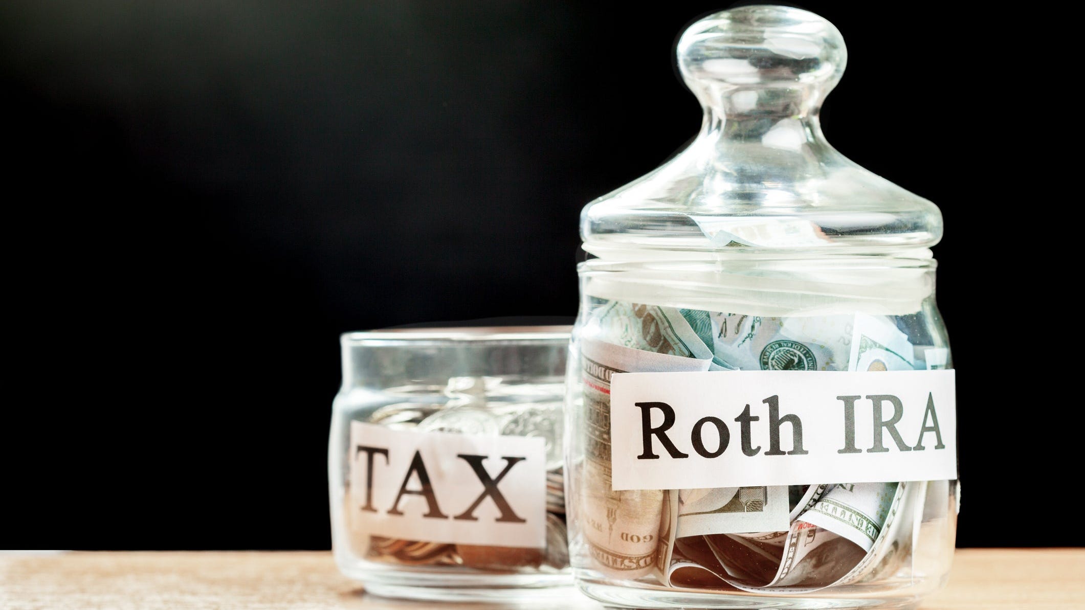 Glass jar used for saving US dollar bills and notes for IRA retirement fund.