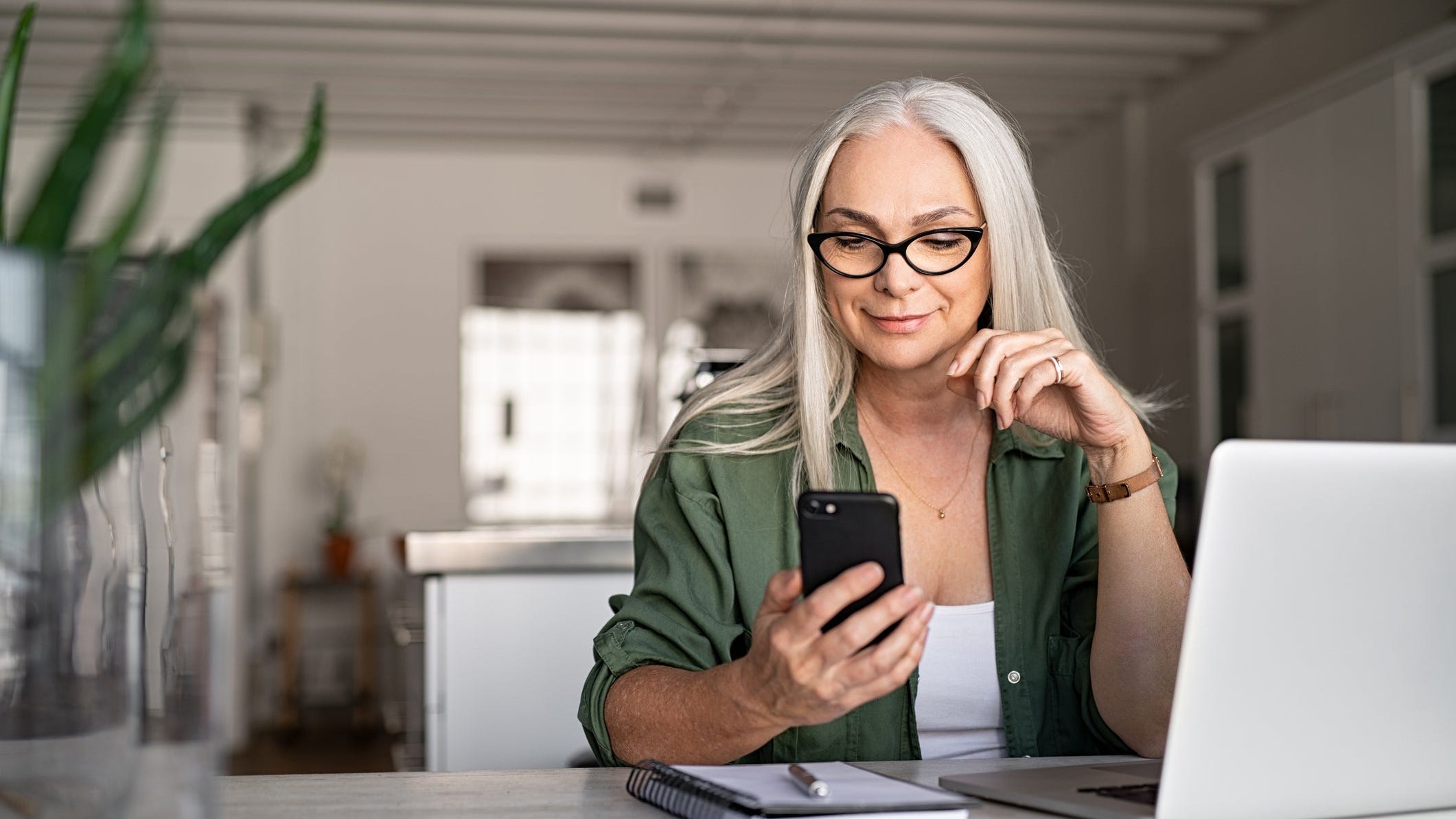 A smiling older woman checks her smartphone.