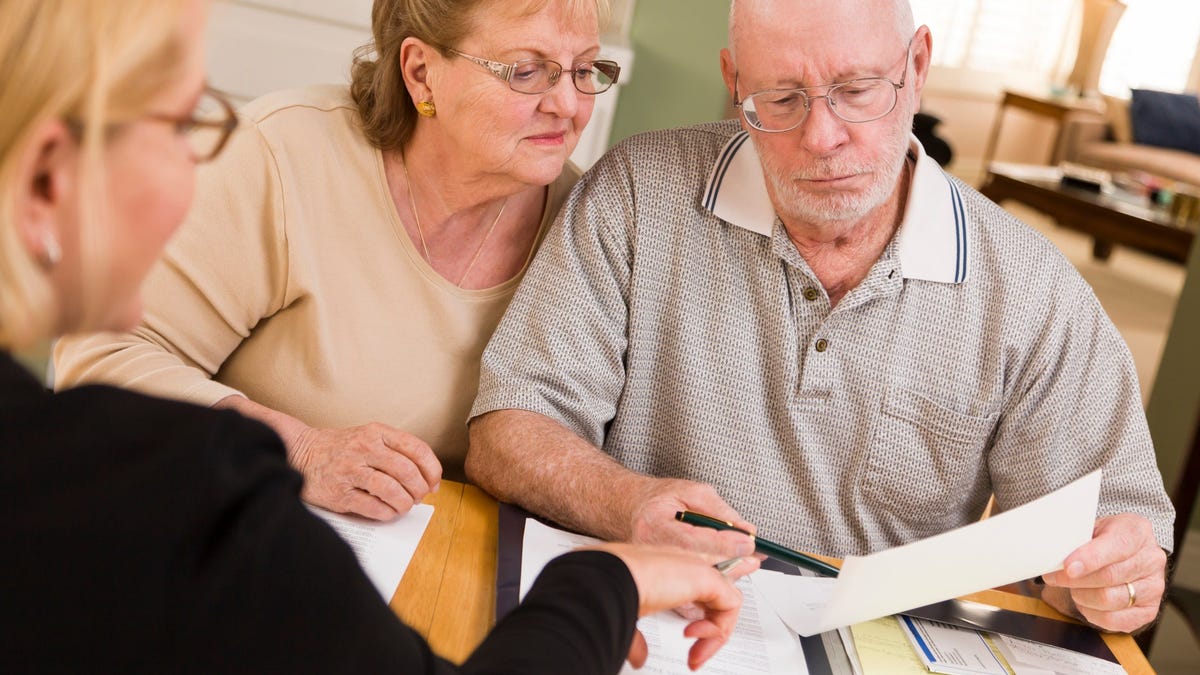 Older couple reviewing financial paperwork with advisor.