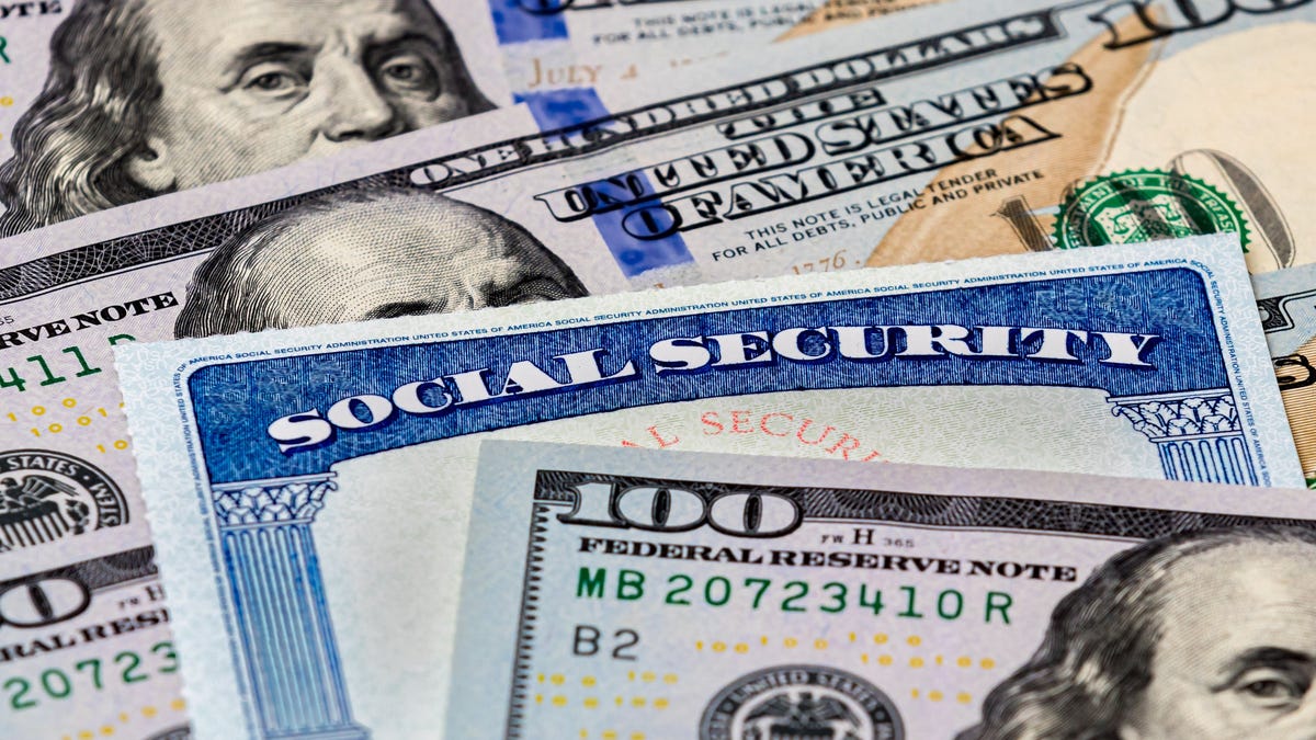 Social Security card nestled into a pile of hundred-dollar bills
