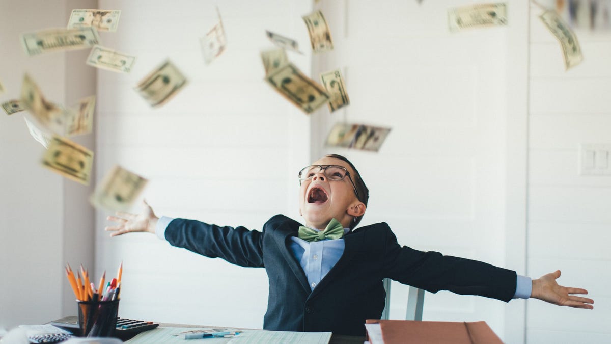 Child in a suit celebrating and throwing money in the air.