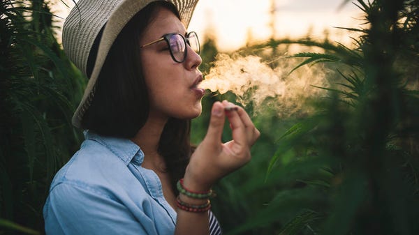 Person in hat and glasses smoking a marijuana ciga