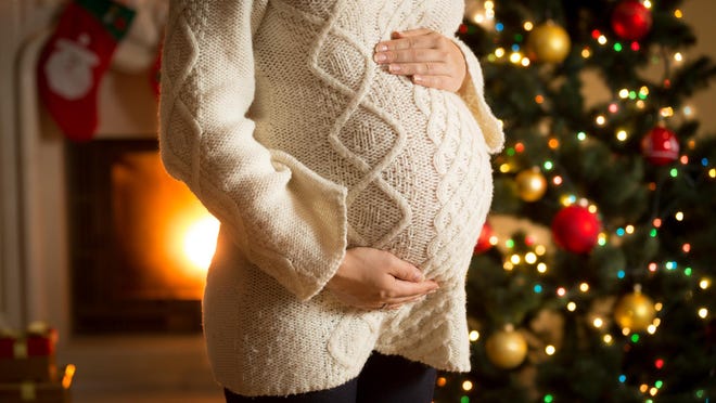pregnant woman posing against fireplace and Christmas tree
