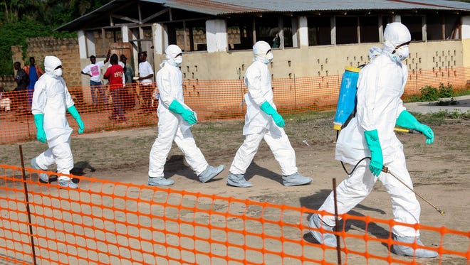 Liberian health workers in protective gear on the way to bury a woman who died of the Ebola virus from the isolation unit in Foya, Lofa County, Liberia, July 2, 2014.