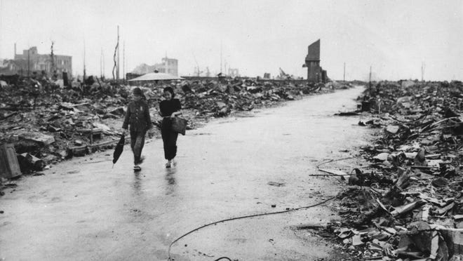 Two people walk through Hiroshima, Japan, a month after the first atomic bomb in history was dropped on the city.