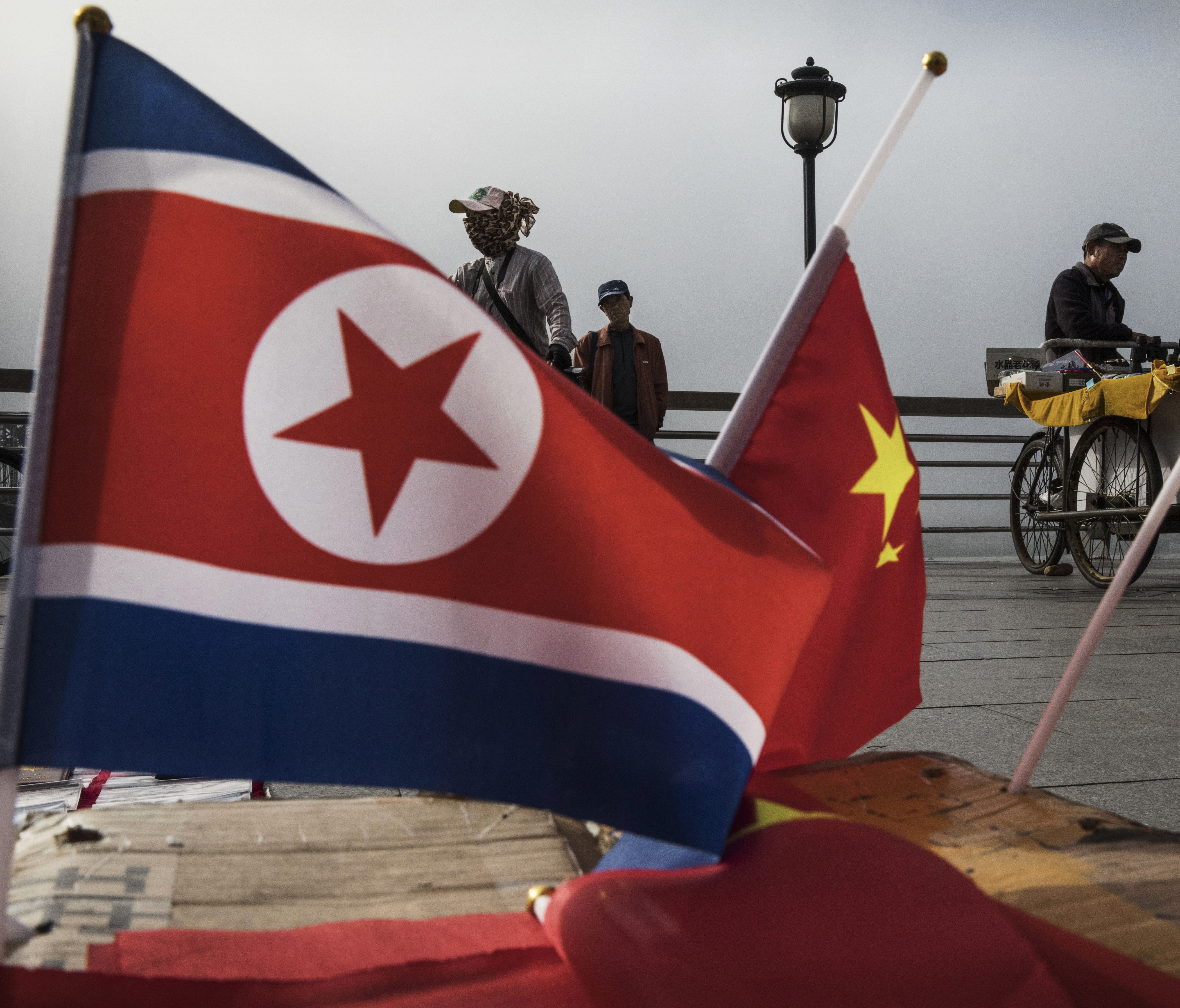 Chinese vendors are pictured selling North Korea and China flags on the boardwalk next to the Yalu river in the border city of Dandong, Liaoning province in northern China.