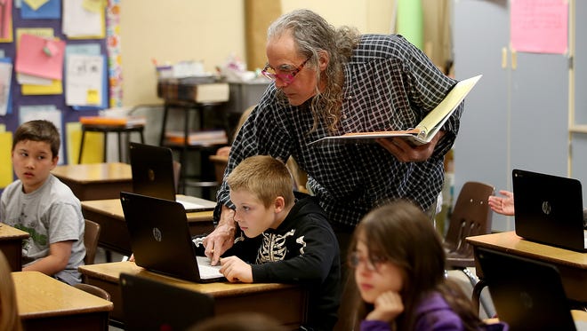 Teacher Leslie (Hart) Nugent helps student Riley Brown log on to his computer during class April 25 at Manchester Elementary School.