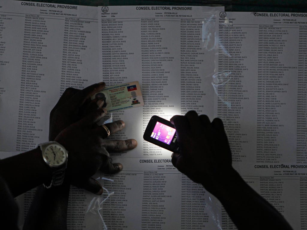 A voter uses his cell phone flashlight to find his name on a voters list during elections in the Petion-Ville suburb of Port-au-Prince, Haiti, Nov. 20, 2016. Haiti's repeatedly derailed presidential election got underway more than a year after an ini