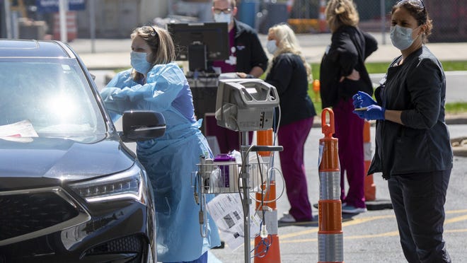 Hospital staff take a patient's vitals before testing for COVID-19 coronavirus while they stay in their car during a trial run for an outdoor emergency triage at Mt. Carmel East hospital on the Far East Side on April 3, 2020.