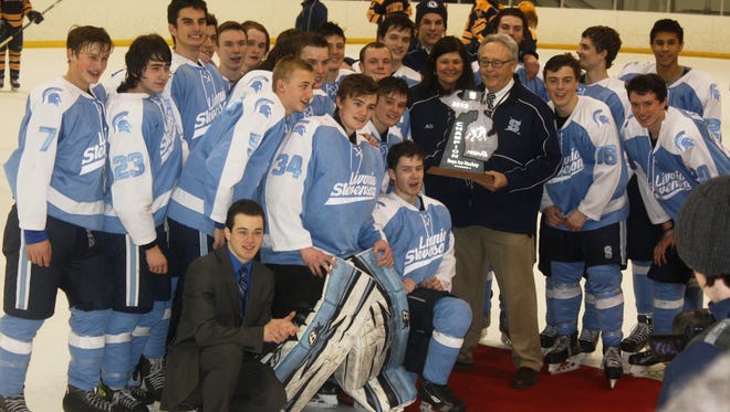 Livonia Stevenson's hockey team poses with its latest Division 2 regional hockey trophy Saturday night.