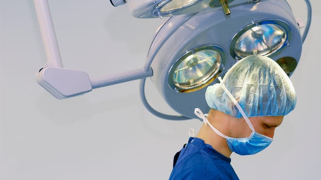Head and shoulders image of doctor in surgical scrubs under operating room light, close-up, part of