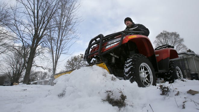 Dave Nebelung, age 46 Ackley street in Westland, uses his Arctic Cat ATV to plow his driveway and the neighbors driveway and the sidewalk along his street in Westland on Friday, January 9, 2015. Nebelung says he doesn't mind the snow and loves helping his neighbors out with clearing their snow just the bitter cold is what he dislikes.