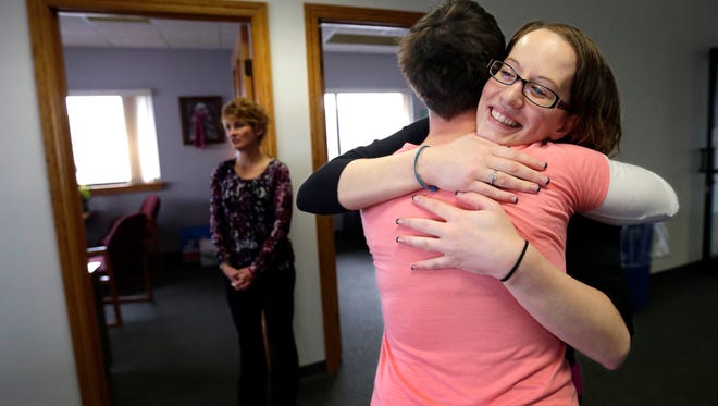 Kristin Hawley, right, gets a hug from Stephanie Dodge as she celebrates her third "sobriety birthday" with colleagues at STEP Industries in Neenah. In back, Michelle Devine Giese, president of STEP Industries, looks on.