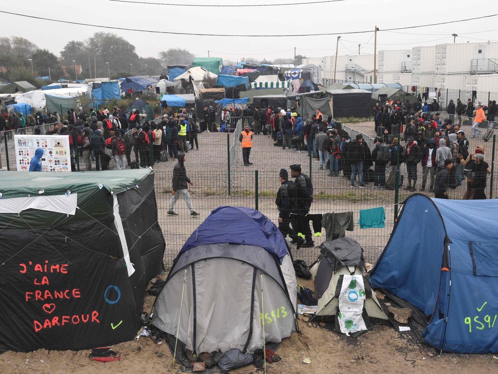 Migrants queue outside a hangar where they will be sorted into groups and put on buses for shelters across France, as part of the full evacuation of the Calais 'Jungle' camp, in Calais, northern France, on Oct. 24, 2016. French authorities are set to