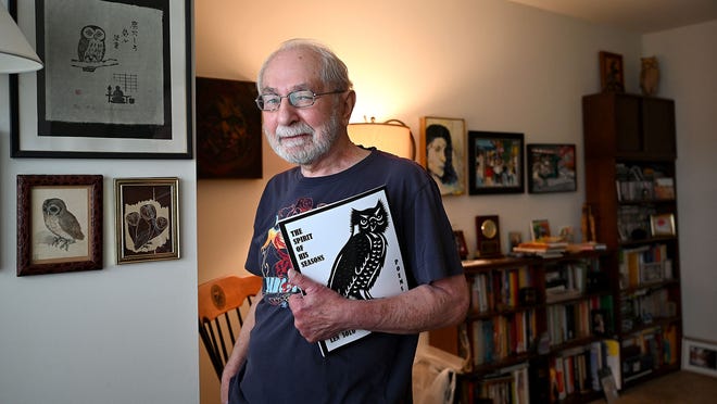 Len Solo with a copy of his latest book of poetry, "The Spirit of His Seasons," in his Marlborough study. Solo is also a painter and some of his work hangs in the study.