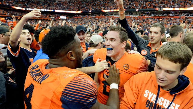 Syracuse quarterback Eric Dungey, center right, and linebacker Zaire Franklin celebrate their win over Clemson after the second half of an NCAA college football game, Friday, Oct. 13, 2017, in Syracuse, N.Y. Syracuse upset Clemson 27-24. (AP Photo/Adrian Kraus)