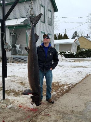 Kyle Jenkins stands with his 143.7 pound, 84.5-inch female sturgeon Tuesday. This was the largest fish caught Tuesday and the longest on record that's been harvested, according to the DNR.